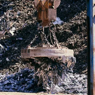 Crane lifting scrap metal in an industrial yard